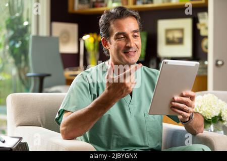 Hispanischer Arzt mit Telemedizin aus seinem Heimbüro, der per Videoanruf auf dem Tablet mit dem Patienten spricht Stockfoto
