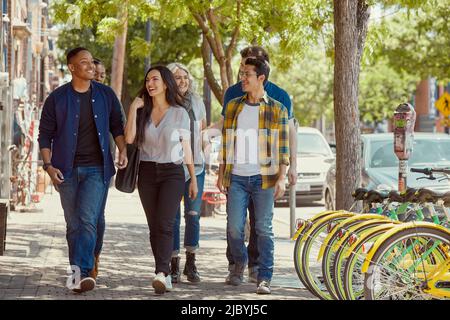 Eine Gruppe junger Mitarbeiter, die gemeinsam den Bürgersteig entlang gehen. Stockfoto
