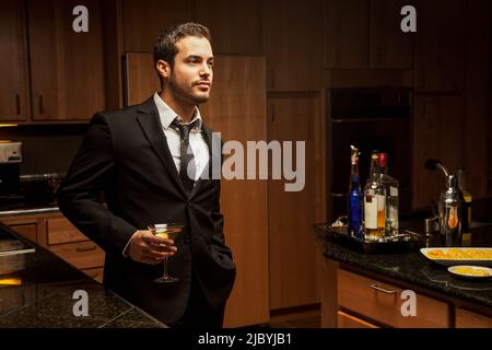 Hispanic Mann trinkt Martini in Küche Stockfoto