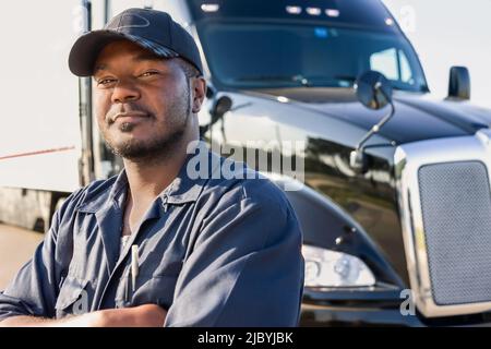 Lächelnder Mann stehend in der Nähe von semi-LKW Stockfoto