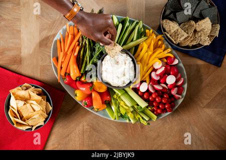 Ein Schuss von einer Person, die einen Chip in saure Creme eintaucht Stockfoto