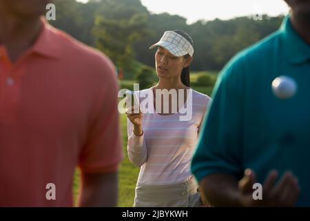 Pilipino Golfer SMS auf Handy Stockfoto