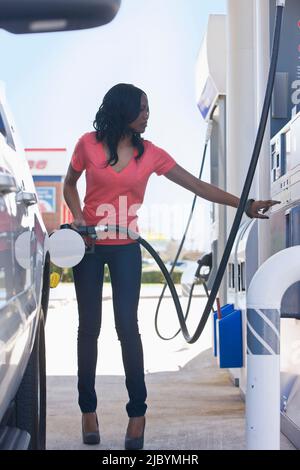 Afroamerikanische Frau Pumpen Gas an Tankstelle Stockfoto