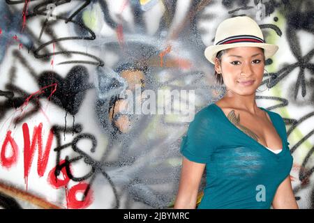 Hispanische Frau, die in der Nähe einer graffidmierten Wand steht Stockfoto