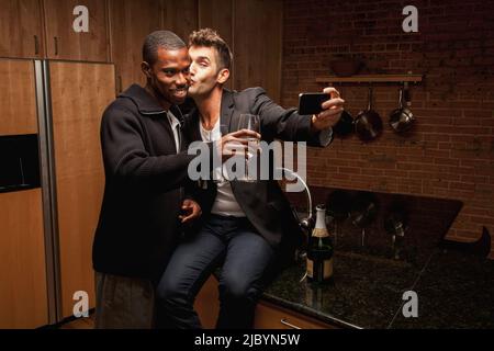 Gay paar trinken Wein in Küche und Selbstporträts zu nehmen Stockfoto