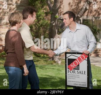 Paar Händeschütteln mit Immobilienmakler Stockfoto