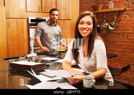 Hispanische Frau, die sich Papierkram in der Küche ansieht Stockfoto