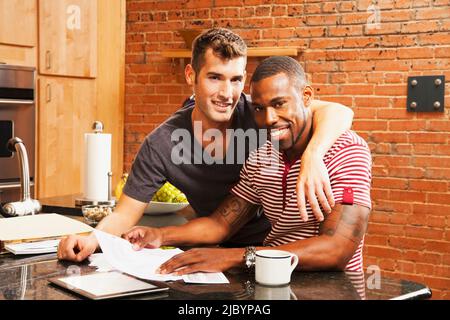 Gay paar Blick auf Papierkram in Küche Stockfoto
