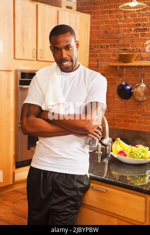 Afroamerikanischer Mann, der sich in der Küche gegen die Theke lehnte Stockfoto