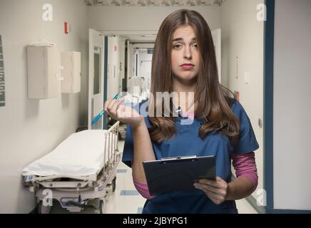 Überarbeitete Krankenschwester hält Zwischenablage in Krankenhaus-Flur Stockfoto