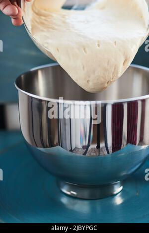 Der Prozess der Herstellung von Weizenbrot zu Hause. Sauerteig für Brot vor dem Kneten. Das Konzept der gesunden hausgemachten Speisen. Vertikales Foto. Stockfoto