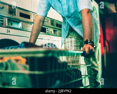 Mann schob Wäschekorb im Waschsalon Stockfoto