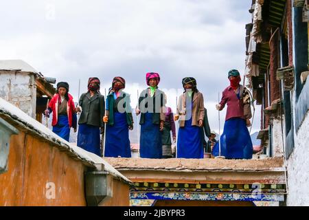 Tibetische Frauen, die auf einer Baustelle im Kloster Drepung arbeiten, singen ein traditionelles tibetisches Lied. Stockfoto