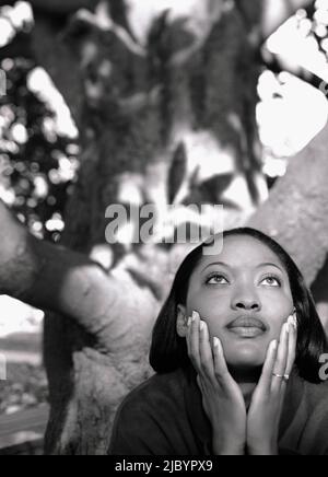 Afrikanische Frau in der Nähe von Baum mit Kopf in Händen Stockfoto