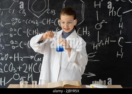 Gymnasiatin, die im Chemielabor experimentiert, Schülerin, die sich um Experimente im Chemieunterricht kümmert, verwenden Sie eine Pipette für Flüssigkeit Stockfoto