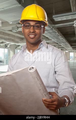 Afrikanische amerikanische Mann, hält Blaupausen auf Baustelle Stockfoto