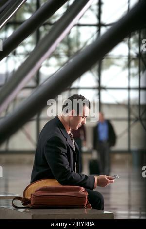 Hispano-Amerikaner Geschäftsmann SMS auf Handy in lobby Stockfoto