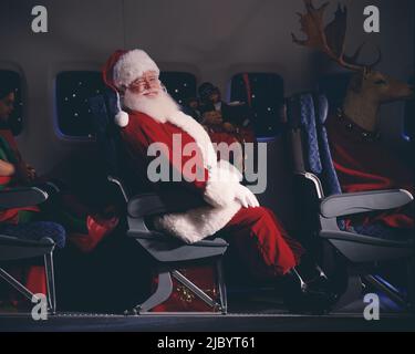 Santa Claus, Elfen, Rentiere und Geschenke in einem Flugzeug Stockfoto