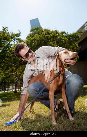 Mann zu Fuß Hund im Stadtpark Stockfoto