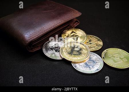 Kryptowährung Wallet, Spar- und Anlagekonzept. Geldbörse mit verschiedenen Krypto-Münzen wie Bitcoin und ethereum auf schwarzem Hintergrund. Stockfoto