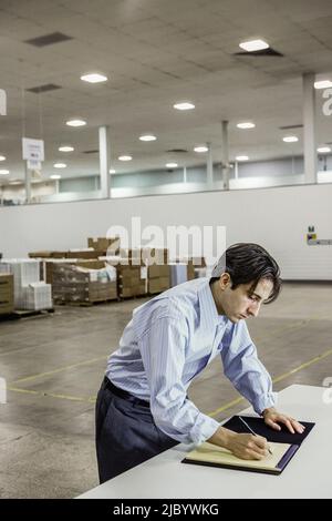 Geschäftsmann schreiben auf Pad im Lager Stockfoto