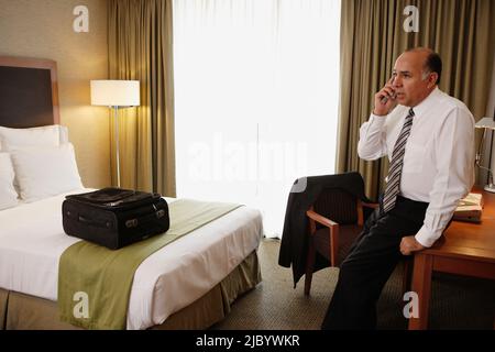Im mittleren Alter Geschäftsmann mit Handy im Hotelzimmer Stockfoto