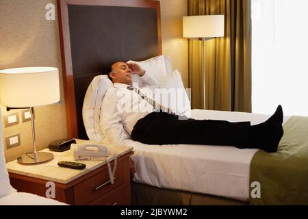 Im mittleren Alter Geschäftsmann auf Bett im Hotelzimmer Stockfoto