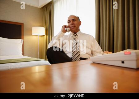 Im mittleren Alter Geschäftsmann mit Telefon im Hotelzimmer Stockfoto