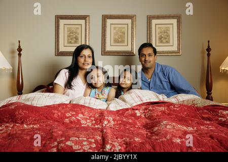 Indische Familie sitzen im Bett Stockfoto