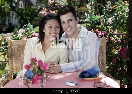 Paar am Gartentisch umarmt Stockfoto