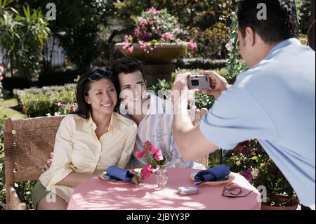 Kellner nehmen Foto des Paares am Tisch Stockfoto