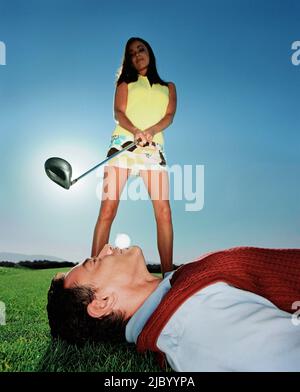 Frau schwingt beim Golfball im Mund des Mannes Stockfoto