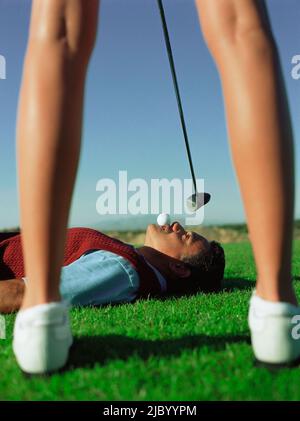 Frau schwingt beim Golfball im Mund des Mannes Stockfoto