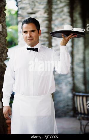Kellner hielt ein Tablett mit Kaffeetassen Stockfoto