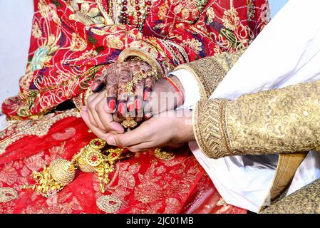 Die Hand einer indischen Braut und eines indischen Bräutigams wird vor den Hochzeitsritualen zusammengebunden Stockfoto