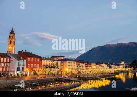 Beleuchtete Stadt Ascona und Alpensee Maggiore in der Dämmerung im tessin, Schweiz. Stockfoto