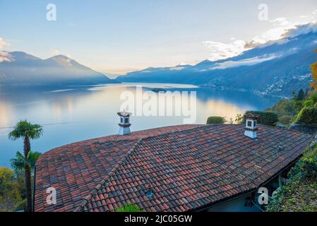 Hausdach und Panoramablick über den Lago Maggiore mit Berg- und Brissago-Inseln im Tessin, Schweiz. Stockfoto