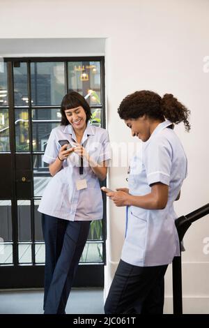 Frauen in der Gesundheitsbranche nutzen Mobiltelefone auf dem Flur Stockfoto