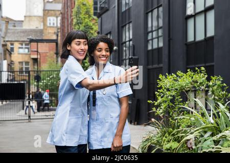 Frauen in der Gesundheitsbranche nehmen Selfie in der Gasse Stockfoto