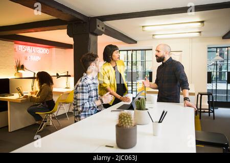 Gruppe diskutiert Projekt im Co-Working-Raum bei Kaffee Stockfoto