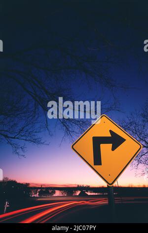 Neon-Streifen von Verkehr und ein Schild mit rechts Richtungspfeil am Straßenrand in der Nähe von einem See, White Rock Lake, Dallas, Texas, USA Stockfoto