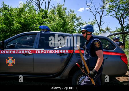 VESELIANKA, UKRAINE - 7. JUNI 2022 - ein EOD-Experte des Staatlichen Notdienstes der Ukraine trägt während einer Minenräumungsmission Werkzeuge zur Entfernung eines Stockfoto