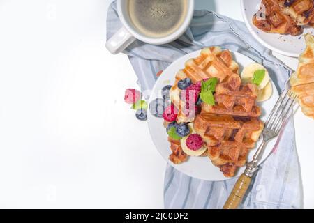 Modernes Dessert-Croffle: Eine Mischung aus Croissants und Waffeln, Waffeleisen-Pfanne mit Waffeleisen, Beerenfrüchten und Schokolade Stockfoto