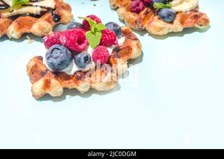 Modernes Dessert-Croffle: Eine Mischung aus Croissants und Waffeln, Waffeleisen-Pfanne mit Waffeleisen, Beerenfrüchten und Schokolade Stockfoto