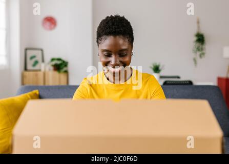 Glückliche afroamerikanische Frau Auspacken Paket nach Online-Shopping Stockfoto
