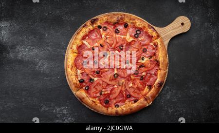 Pepperoni Pizza auf einem runden Holzbrett Stockfoto