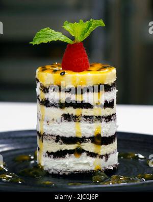Passionsfrucht- und Mango-Mousse-Kuchen mit Schokoladenschicht Stockfoto