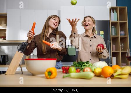 Reife Mutter und ihre Erwachsene Tochter haben Spaß beim Kochen in der Küche Stockfoto
