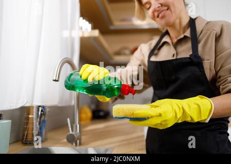 Hübsche Frau in der Küche, die Spülmittel auf Schwamm aufgibt Stockfoto
