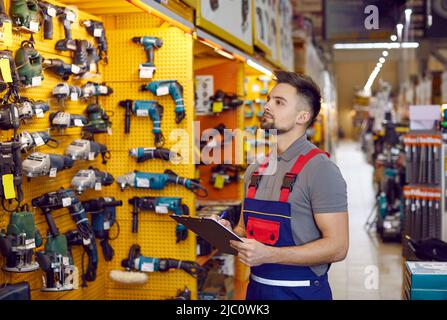 Der Verkäufer, der in einem Baumarkt oder Einkaufszentrum arbeitet, überprüft die Bauwerkzeuge Stockfoto